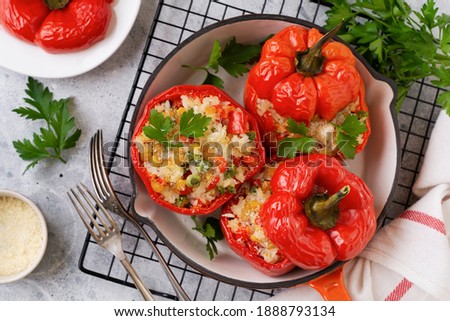 Red bell peppers stuffed with rice and vegetables on cast iron pan on gray concret background. Royalty-Free Stock Photo #1888793134