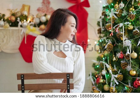 Portrait of beautiful woman in white dress sitting at home,Christmas decorations Background.