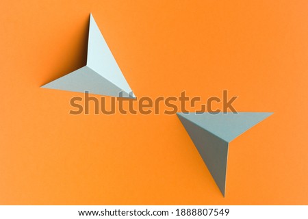 grey paper pyramid , on orange background copy space available. Conflict concept.