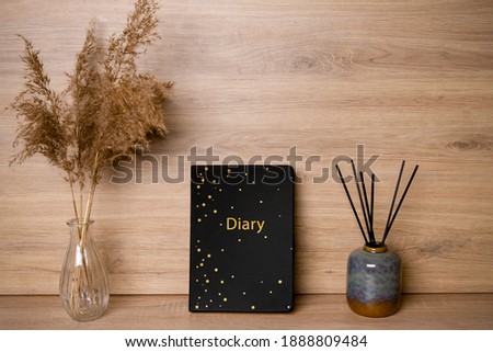 Black diary. The photo. In the interior. For text or image. Nearby are dried flowers and incense sticks..