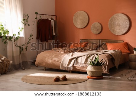 Bed with orange and brown linens in stylish room interior Royalty-Free Stock Photo #1888812133