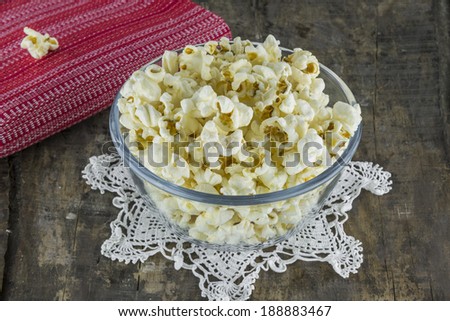 Fresh popcorn in bowl on a  lace doily placed on old wooden table