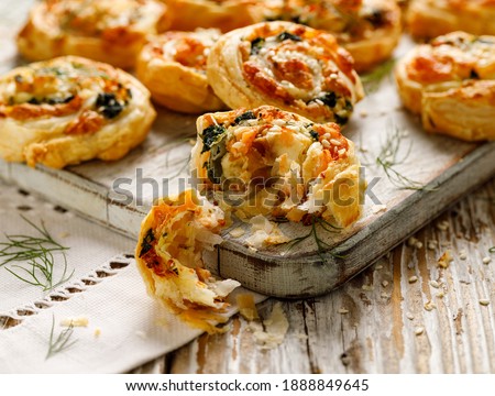 Puff Pastry appetizers Pinwheels stuffed with salmon, cheese and spinach on wooden board close-up Royalty-Free Stock Photo #1888849645