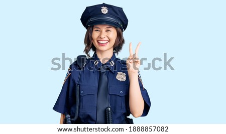 Young beautiful girl wearing police uniform showing and pointing up with fingers number two while smiling confident and happy. 
