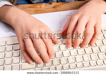 Children hands write on the keyboard on the laptop