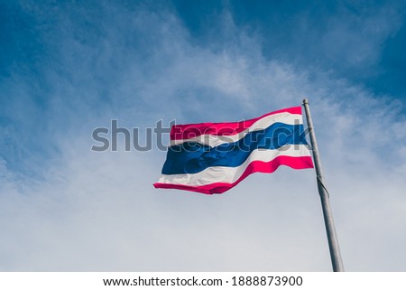 Waving Thai flag of Kingdom of Thailand with blue sky background.