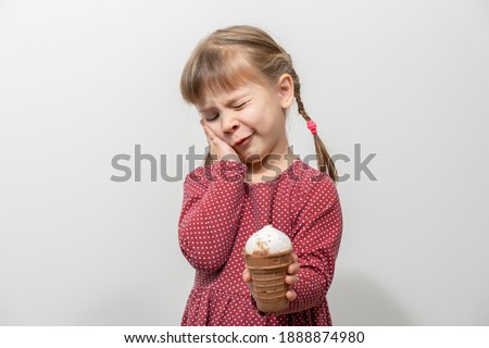 child has a toothache while eating ice cream. sensitivity of teeth to cold Royalty-Free Stock Photo #1888874980