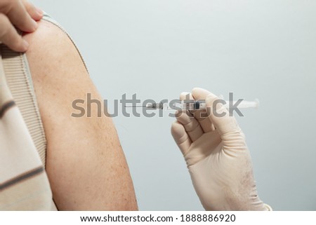 GOIANIA GOIAS BRAZIL - JANUARY 07 2021:  Closeup on nurse hand, with gloves, applying vaccine to elderly patient's arm.
