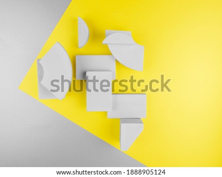Close up abstract grey wooden geometric 3D figures: rectangles, segments of circle, arc on two-tone yellow gray paper backdrop at corner.2021 color concept with copy space.Design layout for text,card
