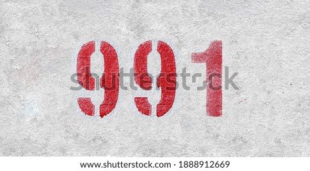 Red Number 991on the white wall. Spray paint.