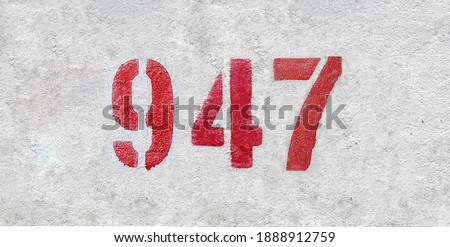 Red Number 947 on the white wall. Spray paint.