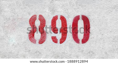 Red Number 890 on the white wall. Spray paint.