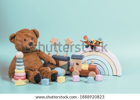 Kids toys collection. Teddy bear, wooden rainbow, train and baby toys on light blue background. Front view Royalty-Free Stock Photo #1888920823