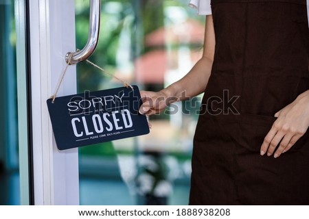 Close up, Asian beautiful woman holding closed sign board hanging on the door of cafe because due to viral infection. Coronavirus 2019 and quarantine concept. go out of business