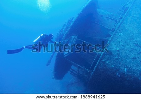 Man scuba diver swimming near the ship wreck in blue deep water. Ship wreck SS Thistlegormm, Red sea Egypt. Royalty-Free Stock Photo #1888941625