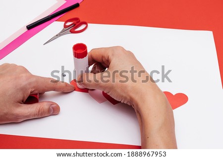 Men's hands make a paper caterpillar of colored paper hearts. Step-by-step instructions, step 12.Gift concept for Valentine's day and Mother's day.