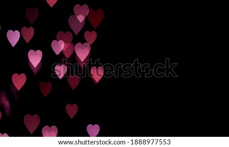 Yellow and pink bokeh in the shape of hearts on a black background copy space. Valentine background