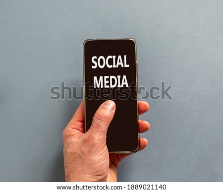 Social media symbol. Male finger clicks on smartphone screen with a words 'social media' on the beautiful blue background. Business and social media concept. Copy space.