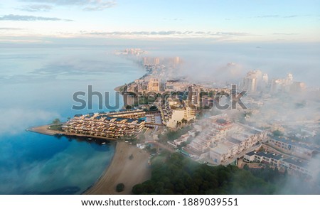 Drone point of view La Manga del Mar Menor cityscape and Mediterranean sea during sunrise, cloudy misty sky, picturesque scenery. Travel, beautiful places concept. Murcia, Spain	
