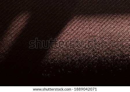 Shadows and light on the upholstery of an old textile brown burgundy sofa.