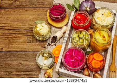 Assorted of fermented vegetables in glass jars. Preserved season vegetables concept, probiotics food for healthy lifestyle. Vintage wooden table, top view Royalty-Free Stock Photo #1889047453