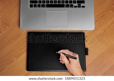 The retoucher is editing images on a graphics tablet. The designer draws on the computer. Workspace of a creative person