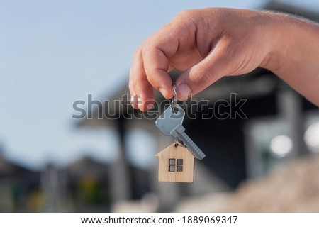 Man holds the keys to the house in his hands against the backdrop of residential buildings. Concept for buying and renting apartments