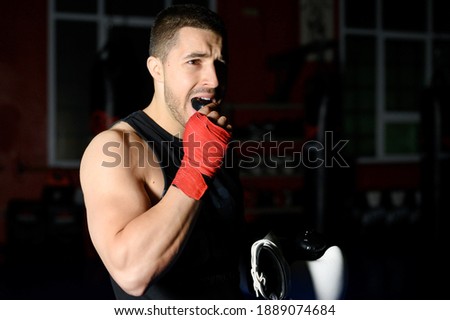 Boxing fighter putting on mouthguard.  Royalty-Free Stock Photo #1889074684