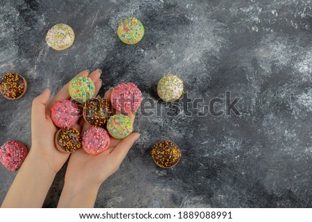 Hands holding colorful sweet small doughnuts with sprinkles