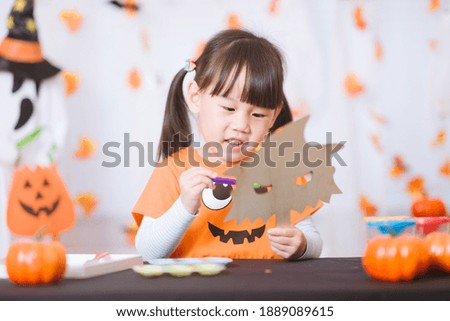 young girl painting witch mask for halloween party at home 