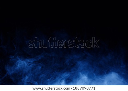 Abstract blue smoke moves on black background. Mystical swirling smoke rolling low across the ground.