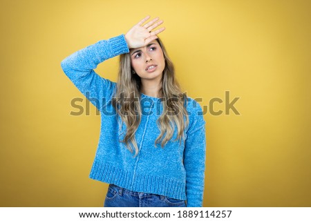 Pretty blonde woman with long hair standing over yellow background Touching forehead for illness and fever, flu and cold, virus sick