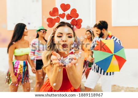 Brazilian Carnival. Young woman enjoying the carnival party blowing confetti Royalty-Free Stock Photo #1889118967