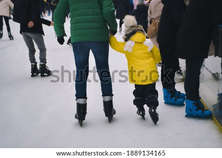 People on the ice rink in the open air spend time, play in the winter.