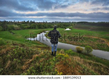 man on the banks of the picturesque river. tourist is enjoying the morning landscape. colorful spring sunrise
