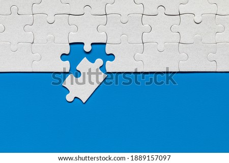 White jigsaw puzzle pieces. Fill in pieces of the jigsaw puzzle. Complete the jigsaw puzzle with the missing pieces. Fragment of a folded white jigsaw puzzle. Royalty-Free Stock Photo #1889157097