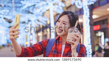 asian female traveler use smart phone to take selfie with pearl milk tea at night while on vacation in Taiwan