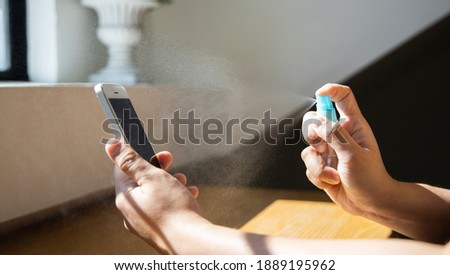Close up young Asian man's hand is spraying an alcohol spray to kill germs on smartphones, Initial protection against germs, Cleaning of electronic appliances or disinfectants during an epidemic. Royalty-Free Stock Photo #1889195962