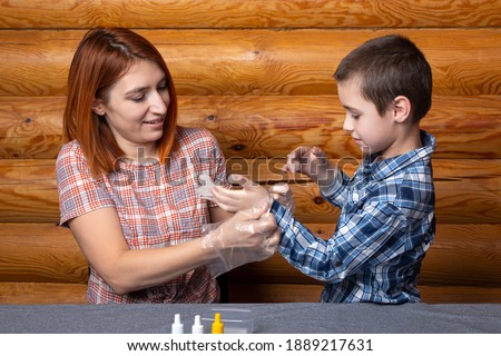 Little boy and mom put on disposable surgical gloves and get ready to do chemical experiments at home