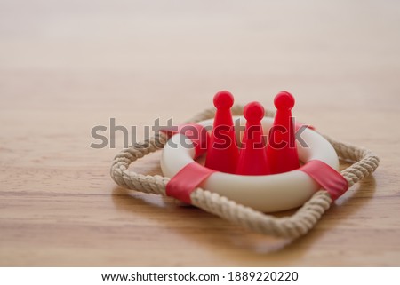 Health insurance or life insurance business and health care concept. People model in lifebuoy on wooden table background copy space. Royalty-Free Stock Photo #1889220220