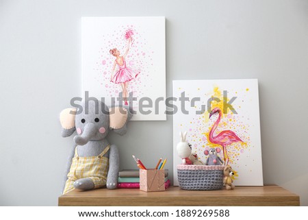 Pictures and stationery with toys on wooden table in children's room. Interior design
