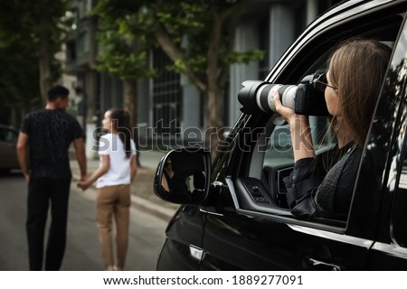 Private detective with camera spying from car