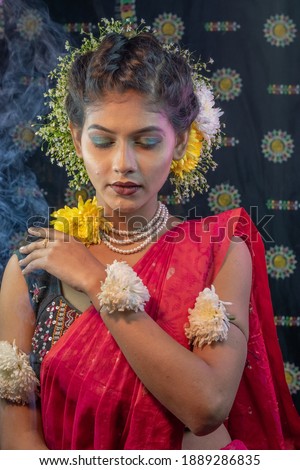 Portrait of beautiful black haired Indian brunette Bengali woman wearing jewellery and petals