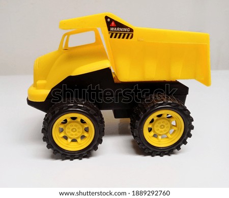 A toy truck in a mix of yellow and black, photographed from the side on a white background.