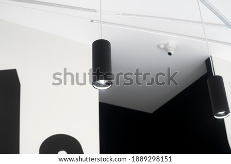 Black lights on the ceiling. Cylindrical luminaires suspended from the ceiling. Commercial space lighting. Royalty-Free Stock Photo #1889298151