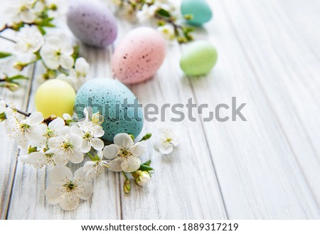 Colorful Easter eggs with spring blossom flowers over wooden background. Colored Egg Holiday border. Royalty-Free Stock Photo #1889317219