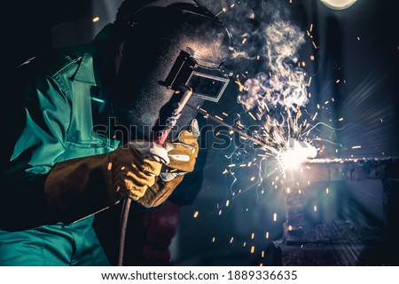 Metal welding steel works using electric arc welding machine to weld steel at factory. Metalwork manufacturing and construction maintenance service by manual skill labor concept. Royalty-Free Stock Photo #1889336635