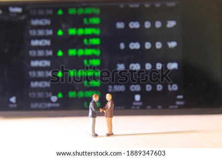 Simple Conceptual Photo, Illustration for Senior Investor Mini Figure Toy Standing 2 businessman Handshaking and watching Running Stock Exchange
