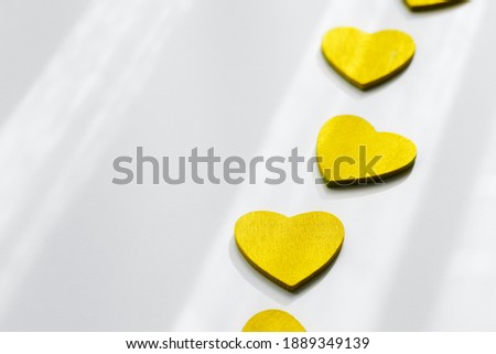 Illuminating yellow heart shape on ultimate grey background with sunlight and shadow. Place for text. Demonstrating trendy colors of year 2021 - Gray and Yellow. Trendy Valentines Day