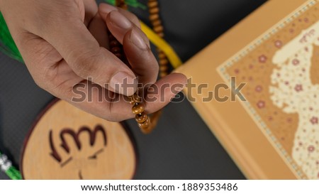 Women's Praying hands with beads or tasbih and tag written in Arabic "Allah" English meaning of God.